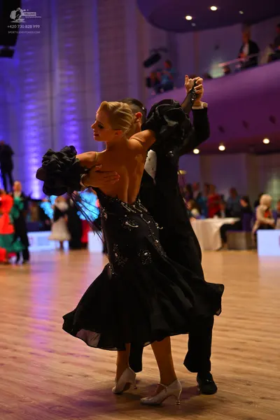 Dancesport competitor: Female dancer: black ballroom dress with voluminous ruffled sleeves and sparklin