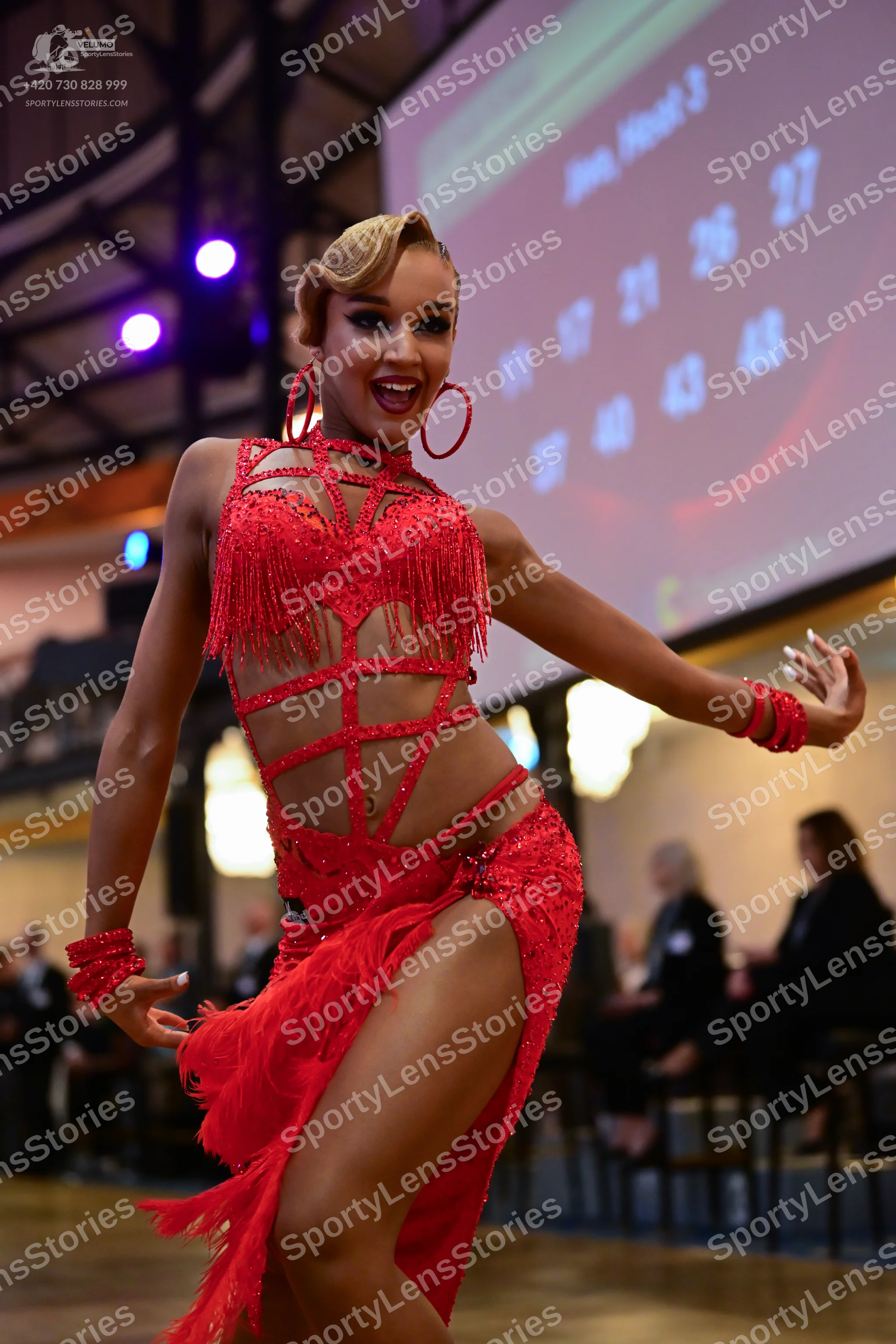 Dancesport competitor: Female dancer: red latin dress with fringe and sequins, featuring cut-outs and s