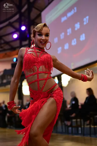 Dancesport competitor: Female dancer: red latin dress with fringe and sequins, featuring cut-outs and s