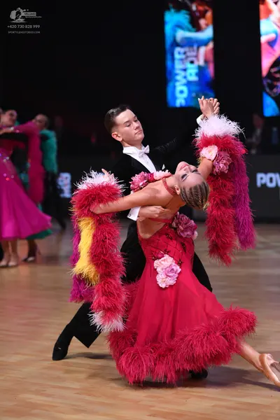 Dancesport competitor: Female dancer: red Latin dress with large pink floral appliqués on the bodice an