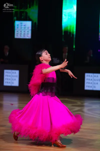 Dancesport competitor: Female dancer: bright pink ballgown with feather-like trim on the hem and sleeve