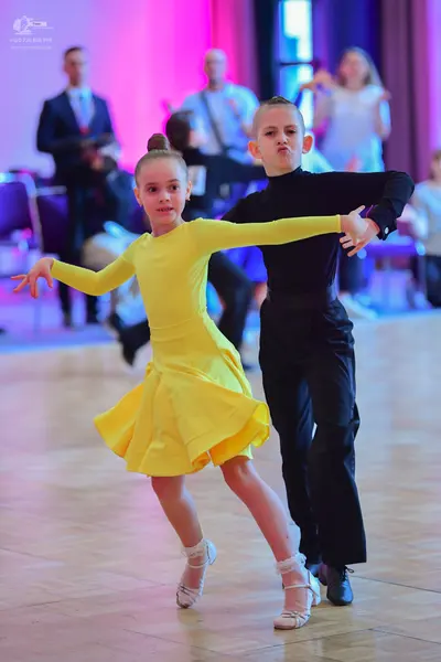 Dancesport competitor: Female dancer: yellow, long-sleeved Latin dress with a flared skirt and white ba