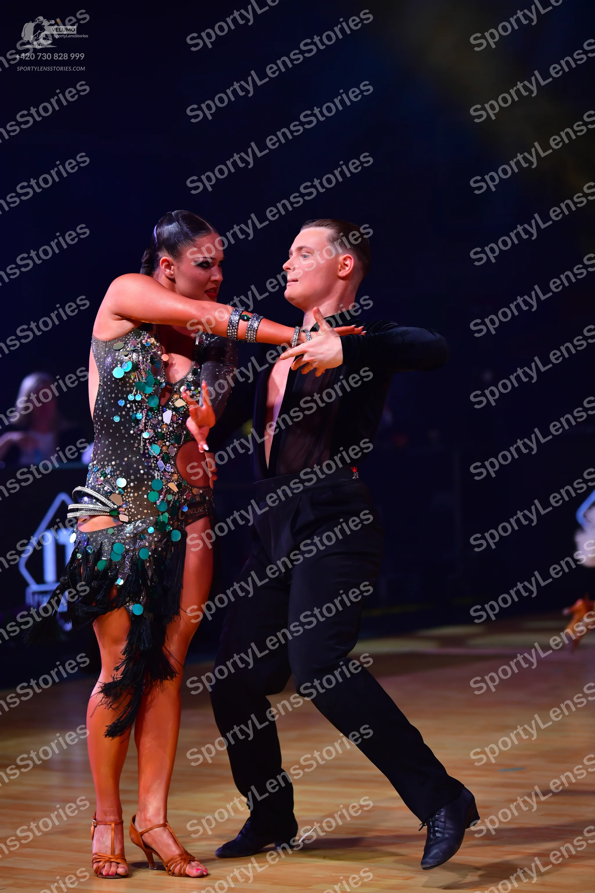 Dancesport competitor: Female dancer: dark green/black Latin dress heavily embellished with large teal