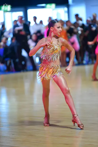 Dancesport competitor: Female dancer: gold two-piece Latin costume with a halter top and short skirt, f