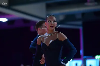 Dancesport competitor: Female dancer: black long-sleeved Latin dress with thin, sparkly straps and a la