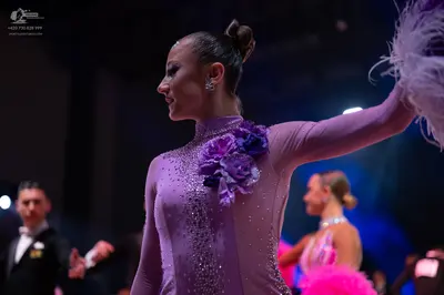 Dancesport competitor: Foreground female dancer: lavender long-sleeved dance dress with scattered rhine