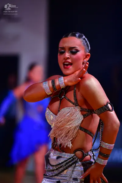 Dancesport competitor: Female dancer (foreground): silver and white latin dance costume with rhinestone
