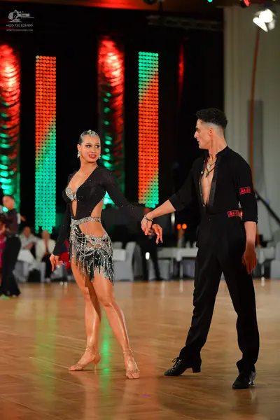 Dancesport competitor: Female dancer: black latin dress with long sleeves, cut-outs at the waist, and s