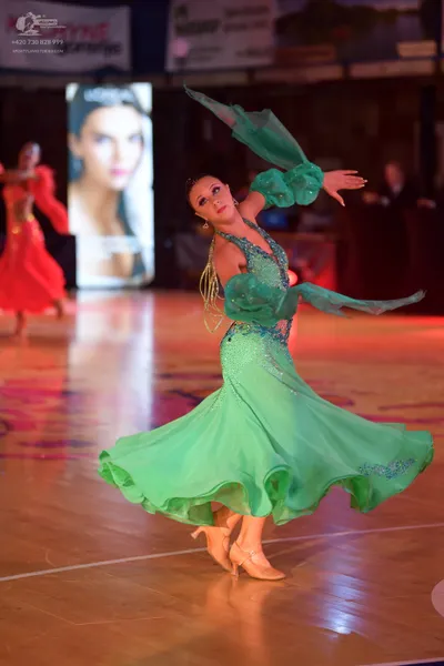 Dancesport competitor: Female dancer in foreground: emerald green latin dress with sequin embellishment