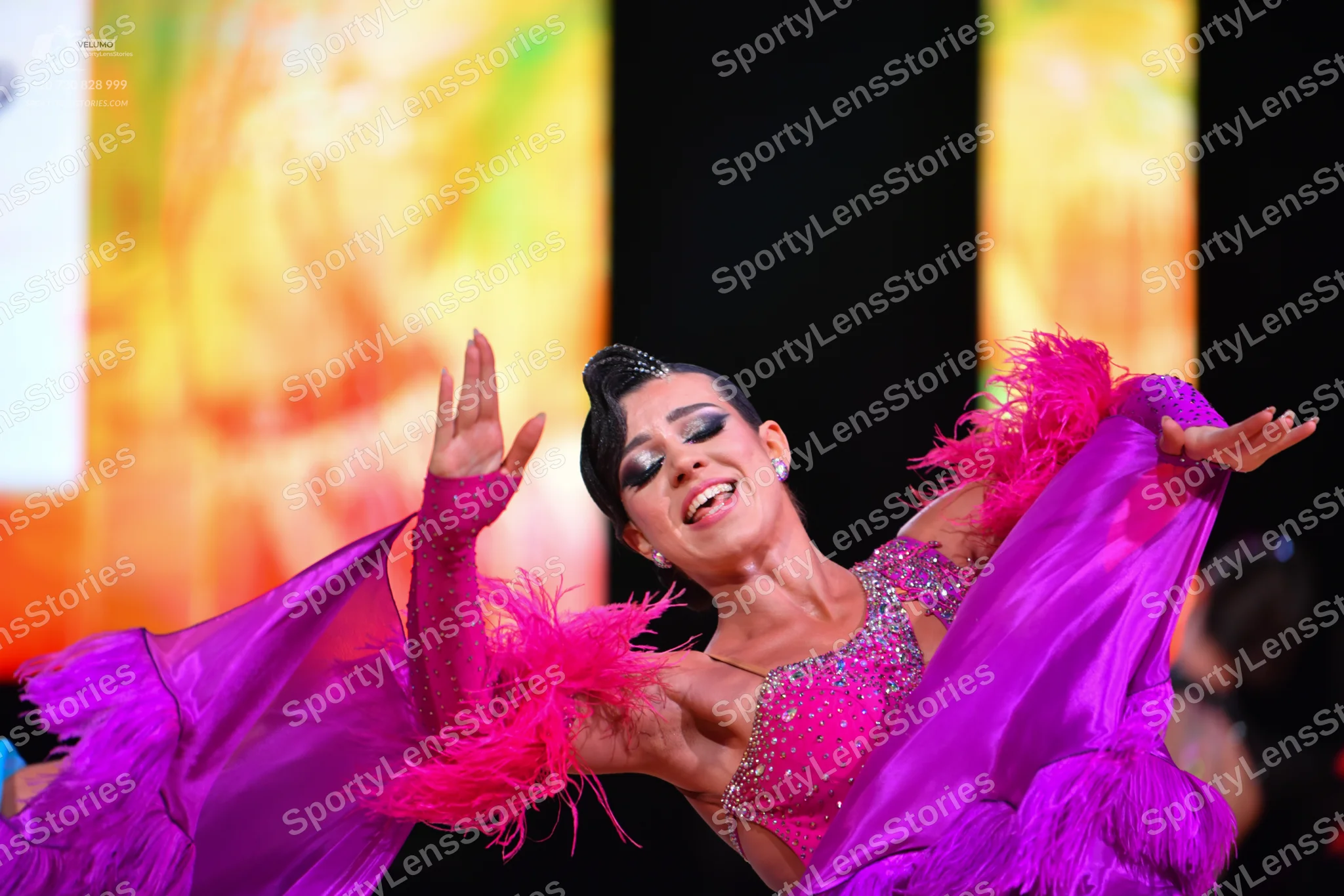 Dancesport competitor: Female dancer: vibrant pink latin dress with a sequined bodice and large, flowin