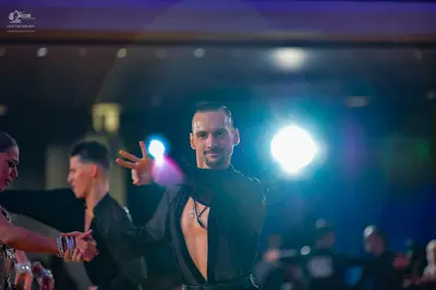 Dancesport competitor: Male dancer in center: black long-sleeved top with an open chest