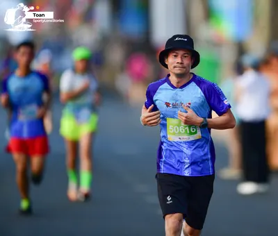 Marathon runner #50616: Runner 1: blue and purple patterned jersey, black shorts, black bucket hat, blac