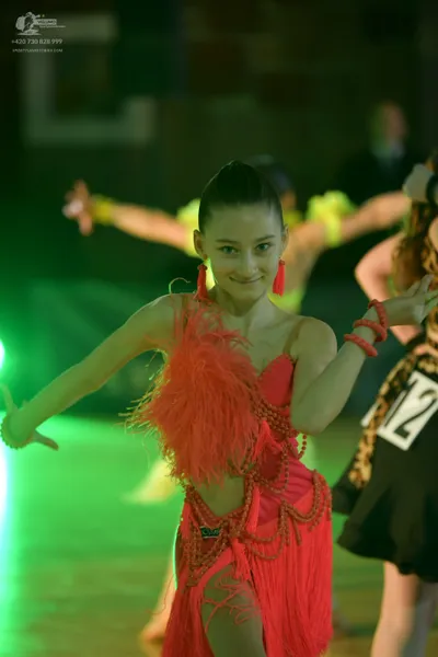 Dancesport competitor #12: Female dancer in foreground: bright pink latin dance dress with fringe, straps, 