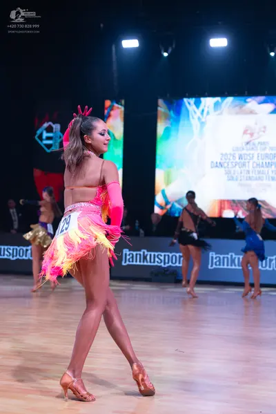 Dancesport competitor: Female dancer in foreground: pink and orange latin dress with long sleeves and p