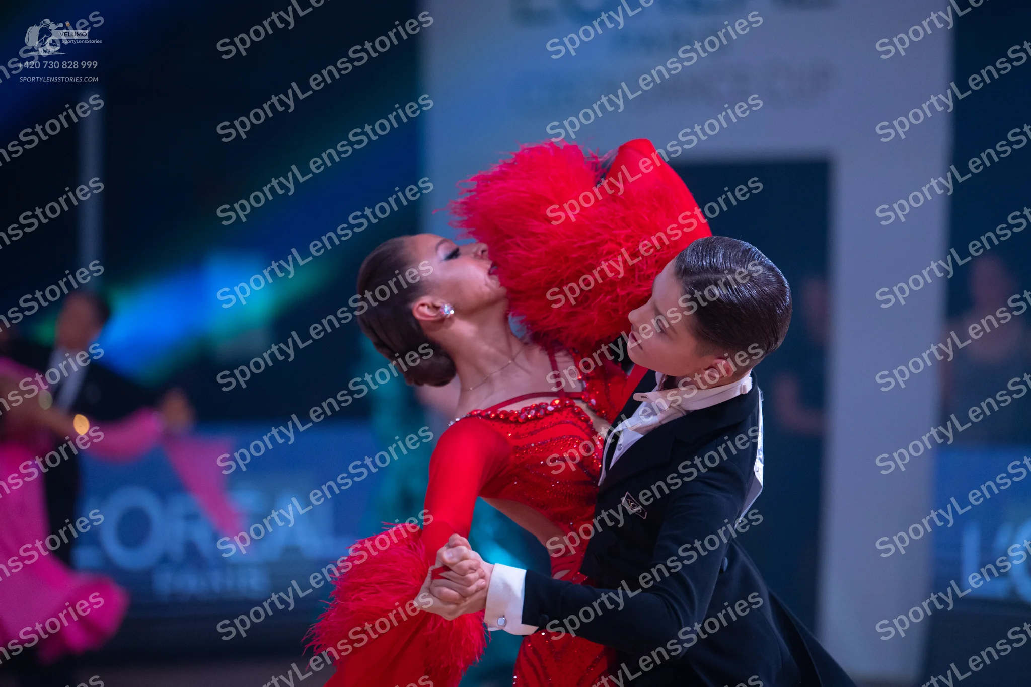 Dancesport competitor: Female dancer: red Latin dance dress featuring red sequins, large red feathers,
