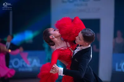 Dancesport competitor: Female dancer: red Latin dance dress featuring red sequins, large red feathers, 