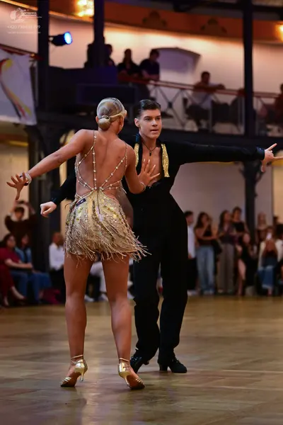 Dancesport competitor: Male dancer: black Latin dance outfit with gold-colored accents on the collar/la