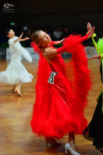 Dancesport competitor #15: Female dancer in foreground: red dress with large, dramatic red feather-like fri
