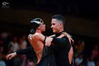 Dancesport competitor: Female dancer: black latin dress with an open back and gold/bronze metallic acce