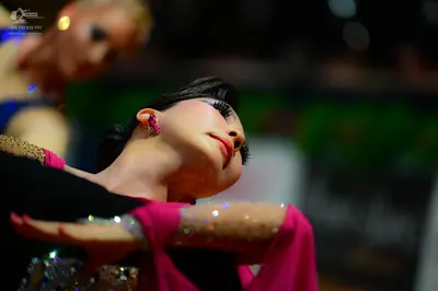 Dancesport competitor: Female dancer in foreground: black and bright pink/magenta latin dress with sequ