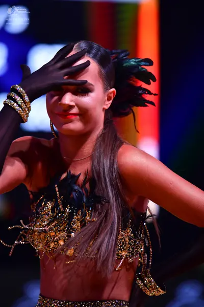 Dancesport competitor: Female dancer: black two-piece latin costume featuring a crop top and matching b
