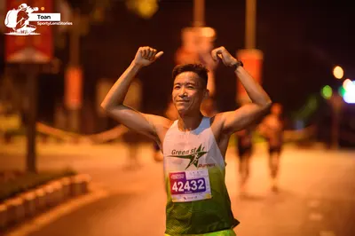 Marathon runner #42432: Runner 1: white and green tank top, dark shorts, black wristband