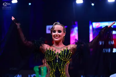 Dancesport competitor: Female dancer: black and gold Latin dress with sequin patterns on the bodice and