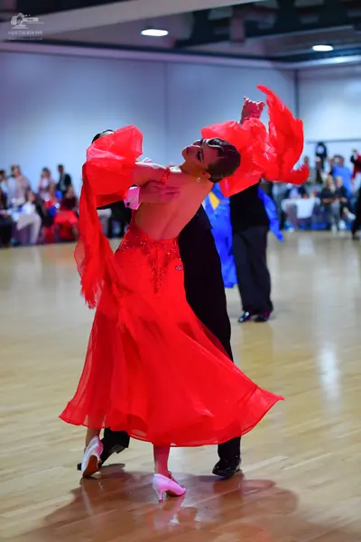 Dancesport competitor: Female dancer: red Latin dress with a sequin-embellished bodice and flowing chif