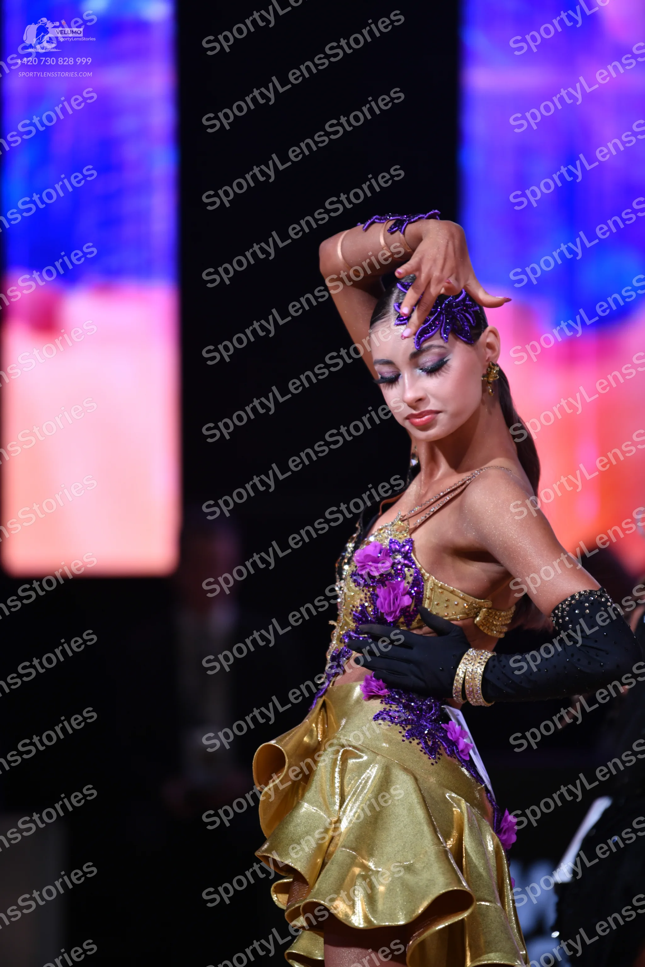 Dancesport competitor: Female dancer: gold latin dress with purple floral embellishments and a ruffled
