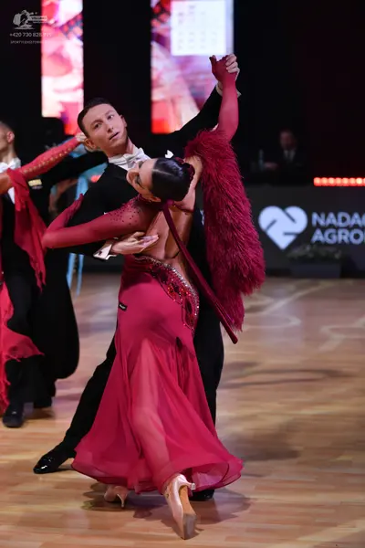 Dancesport competitor: Female dancer: magenta long-sleeved Latin dress with sequin embellishments and a