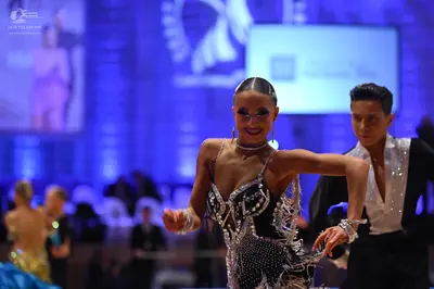 Dancesport competitor: Female dancer in foreground: black latin dress with heavy silver/white sequin an
