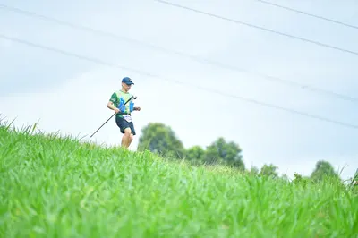 Marathon runner: Runner 1: green and white patterned jersey, dark shorts, blue cap, and holding t