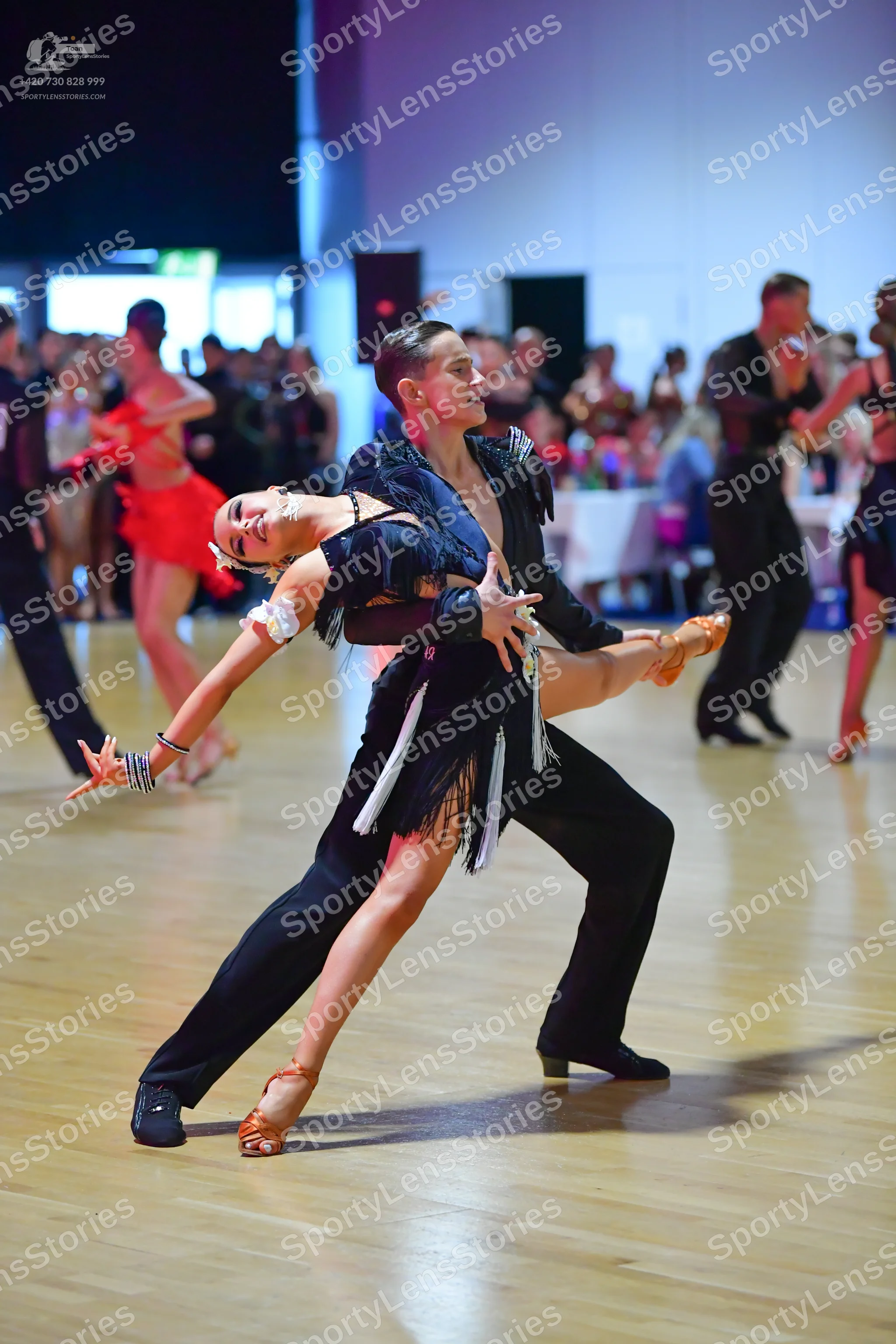 Dancesport competitor: Main female dancer: black Latin dance dress with long white fringe and tan dance