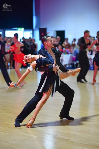 Dancesport competitor: Main female dancer: black Latin dance dress with long white fringe and tan dance