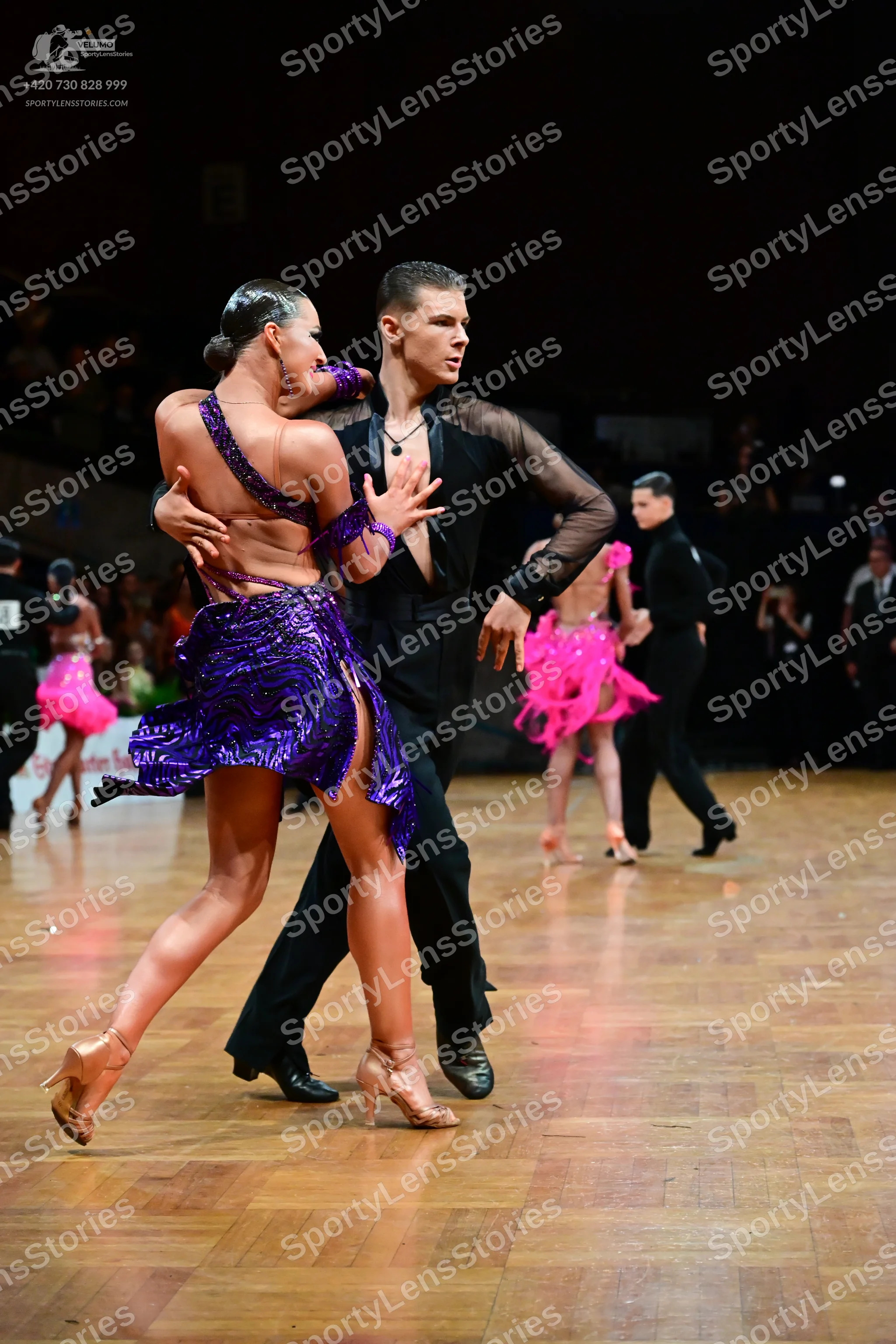 Dancesport competitor: Main female dancer: purple sequined Latin dress with spaghetti straps and a high