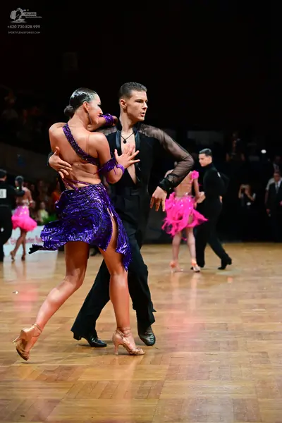 Dancesport competitor: Main female dancer: purple sequined Latin dress with spaghetti straps and a high