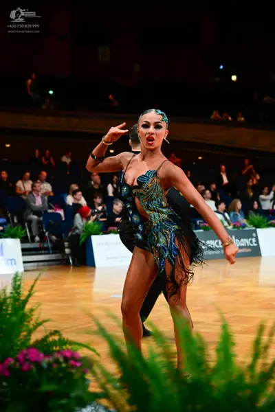 Dancesport competitor: Female dancer: dark Latin dance dress with colorful sequin/bead embellishments i