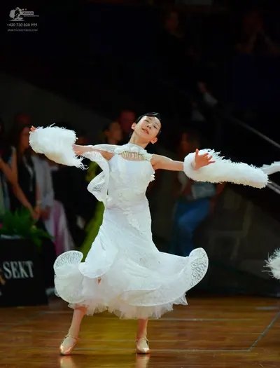 Dancesport competitor: Female dancer: white ballgown with a voluminous, layered lace/ruffled skirt and 