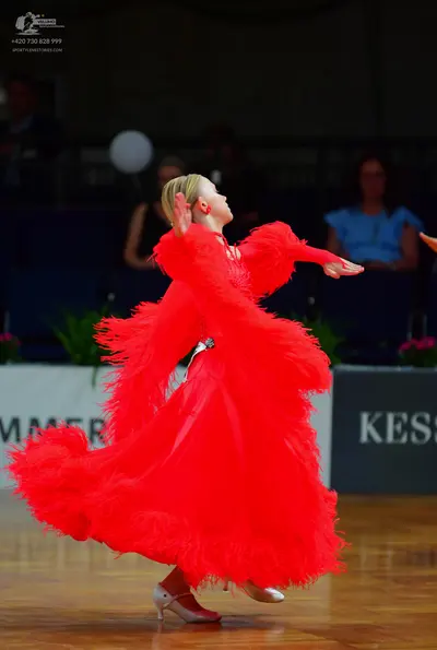 Dancesport competitor: Female dancer: bright red ballroom dress with a large, voluminous feathery skirt
