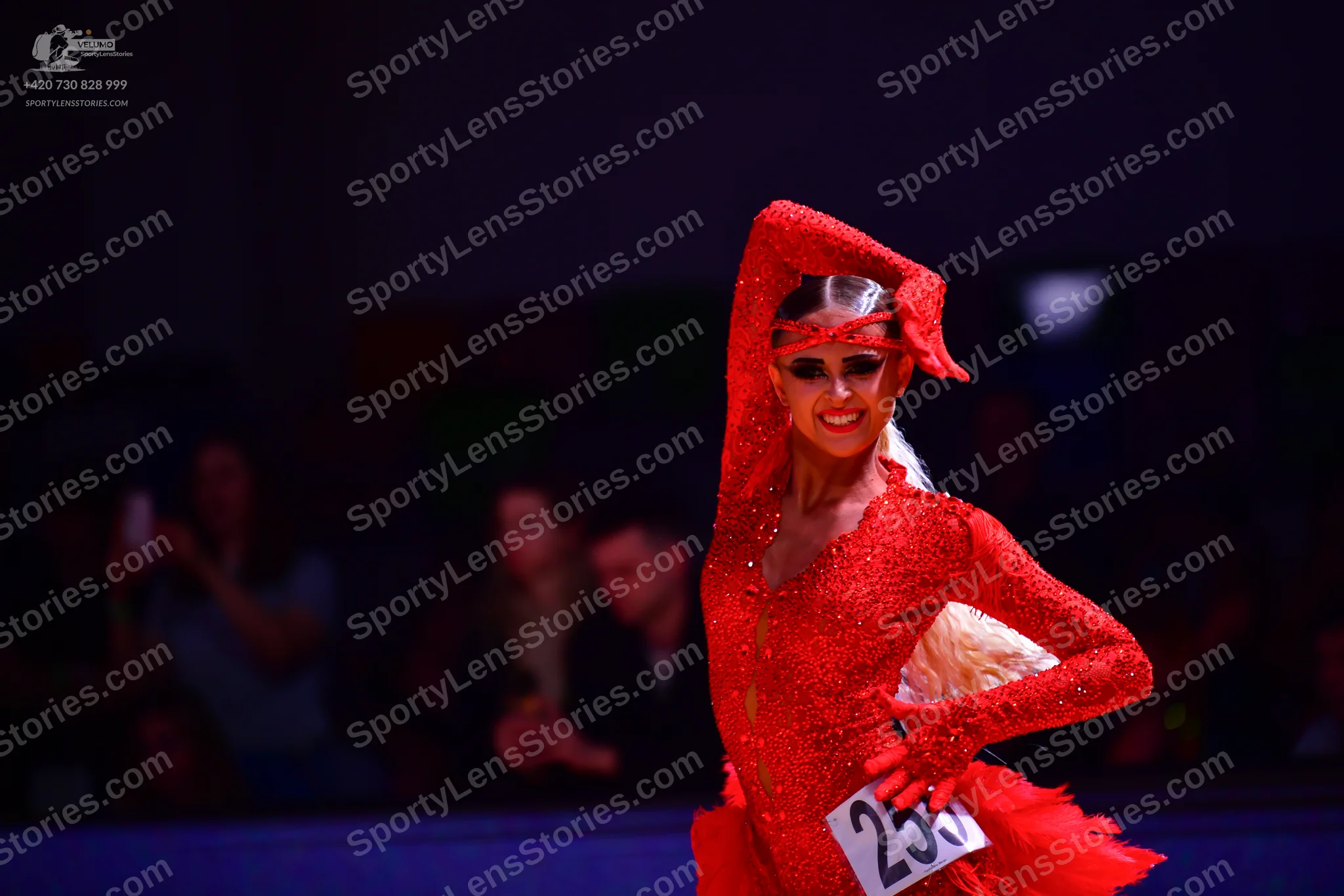 Dancesport competitor: Female dancer: red latin dress with sequins and a matching red headpiece/draped 
