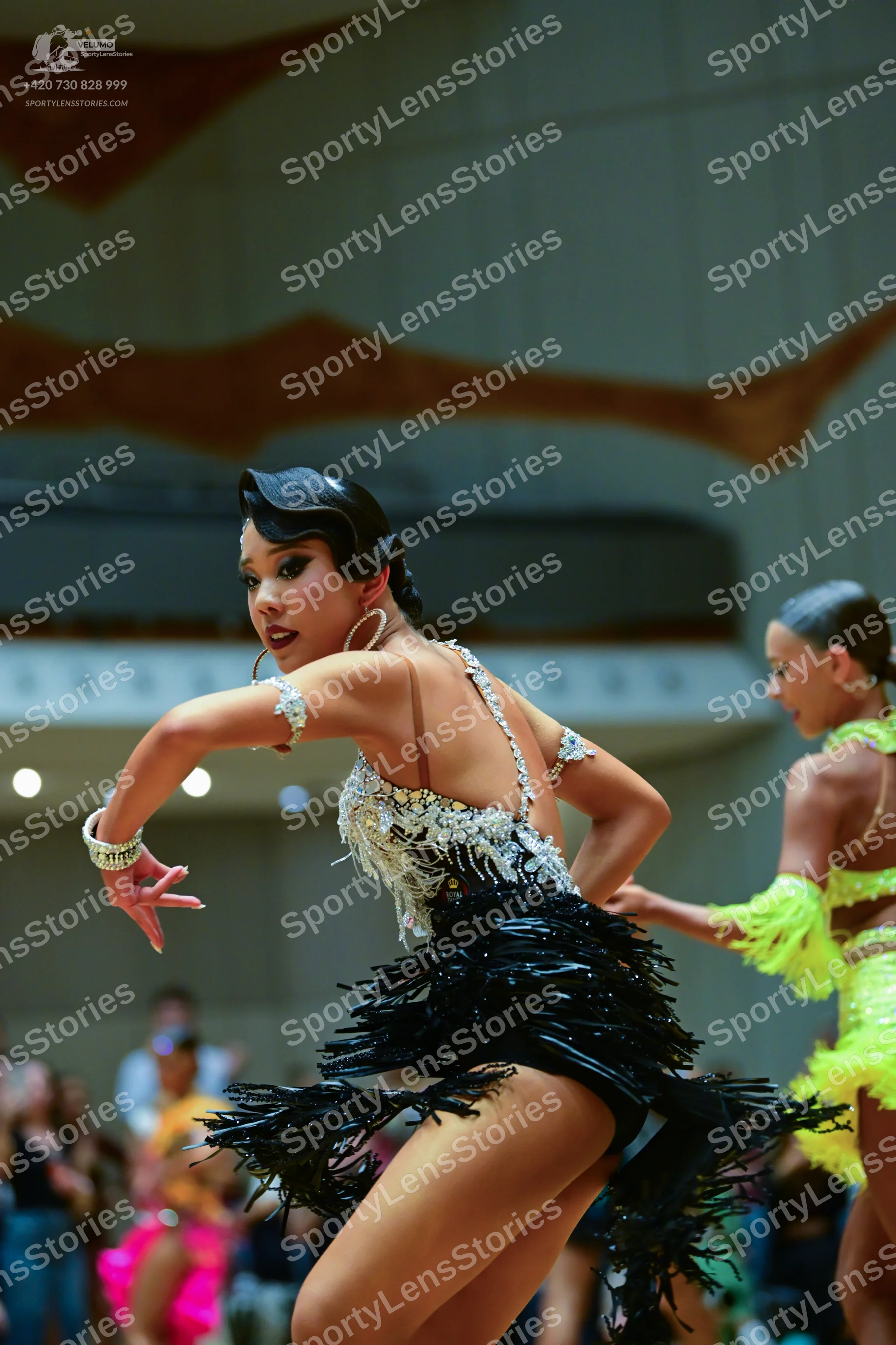 Dancesport competitor: Female dancer 1: Black Latin dance dress featuring a white and silver sequined/b