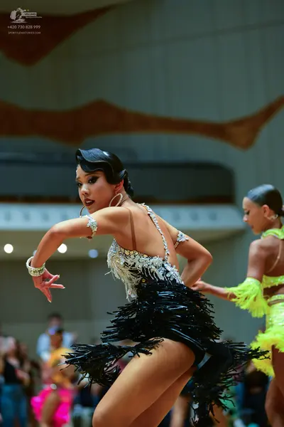 Dancesport competitor: Female dancer 1: Black Latin dance dress featuring a white and silver sequined/b
