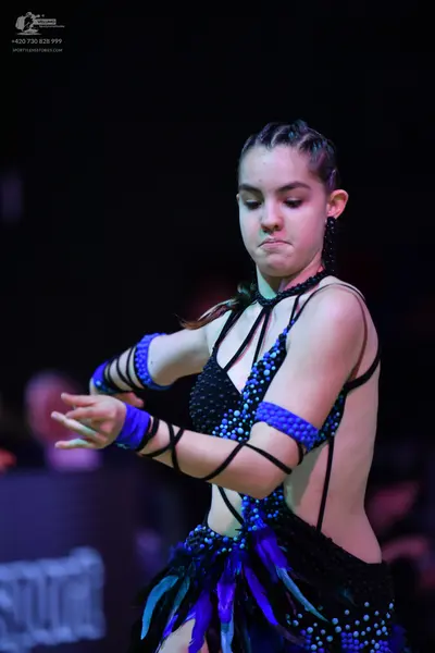 Dancesport competitor: Female dancer: black latin dress with blue sequins, black fringe, and thin black