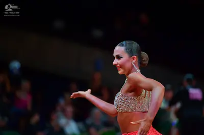 Dancesport competitor: Female dancer: two-piece Latin dance costume featuring a silver/clear sequined/c