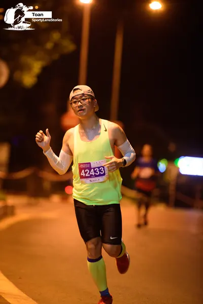Marathon runner #42433: Runner 1: light yellow tank top, black shorts, white arm sleeves, light cap, gla