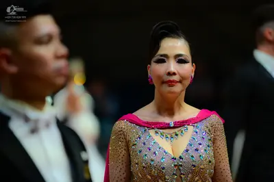 Dancesport competitor: Female dancer: nude-colored mesh Latin dress with pink fabric draped over the sh