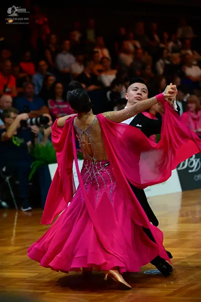 Dancesport competitor: Female dancer: vibrant pink ballroom dress with a heavily embellished gold/sequi