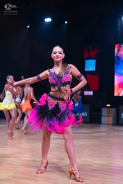 Dancesport competitor: Foreground dancer: black and magenta/pink Latin dance costume with sequins, cut-