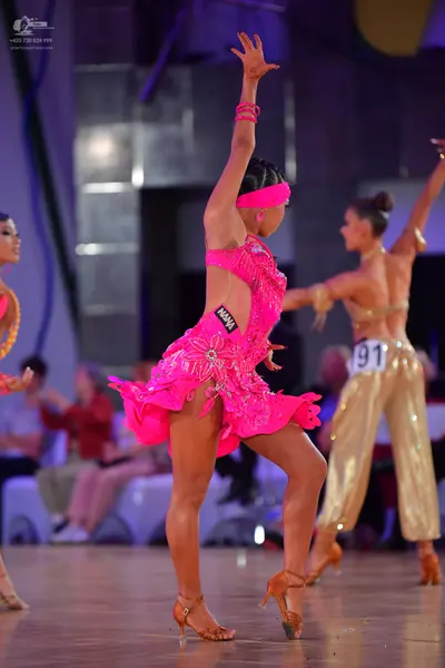 Dancesport competitor #91: First dancer: bright pink latin dress with sequins and ruffles, pink headband an