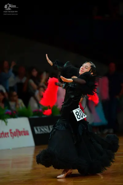 Dancesport competitor: Female dancer: black ballgown with a voluminous, feathery skirt and sleeves
